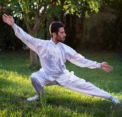 Une personne pratique le tai chi en extérieur